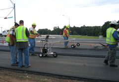 Workers use the second-generation infrared sensor bar on a paving project