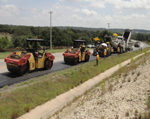 Roadway construction crew installing thin asphalt pavement.