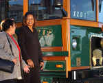 Two ladies standing next to a transit bus.