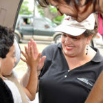 Irene Rodriguez high fives a child in a safety seat.
