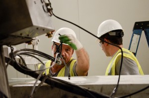 Two workers install a de-freezing device on a concrete truck.