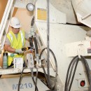 A worker installs a de-freezing device on a concrete truck.