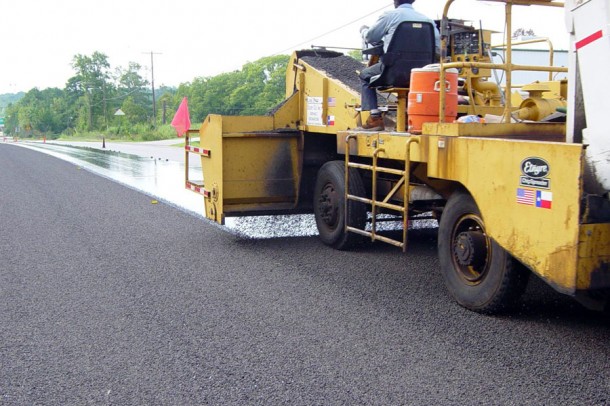Distributor applying aggregate on a roadway.