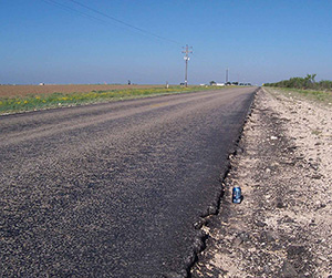 Roadway shoulder degradation caused by heavy truck traffic.