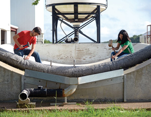 Two researchers installing a sediment retention device for evaluation using the SEC Lab's testing flume.