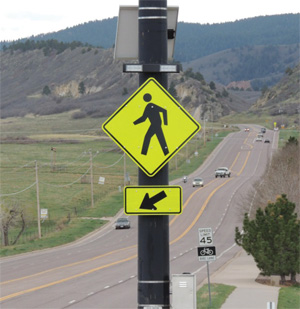 signage for a pedestrian crosswalk with a rectangular rapid-flashing beacon mounted with it