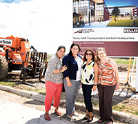 TTI employees taking a moment for a photo in front of a billboard announcing the site as the future headquarters of TTI