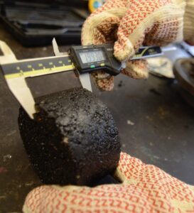 A caliper measuring a test section of asphalt.