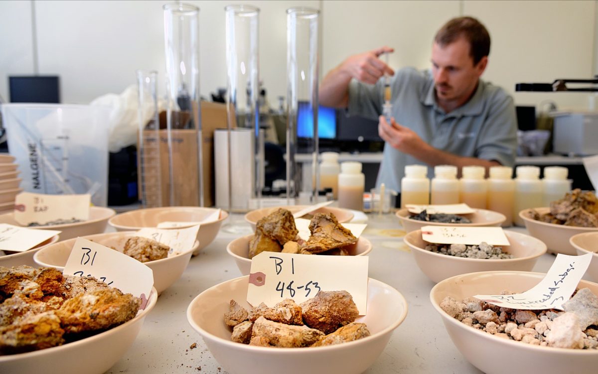 A lab technician inspects aggregate and soil samples inside the soil/umbound materials innovation lab.
