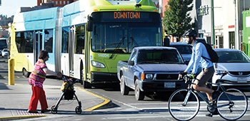 Intersection highlighting multimodal transportation: personal vehicle, city bus, walking, bicycle.