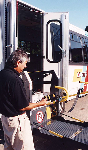 Transit bus operator lowering the wheelchair access ramp on his bus.