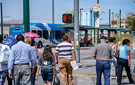 Pedestrians at a crosswalk headed toward a Sun Metro bus stop.