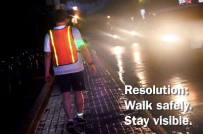 Person walking at night wearing a reflective safety vest.