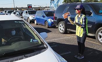 Volunteer reminding drivers waiting in a line of traffic about the U.S. decennial census.