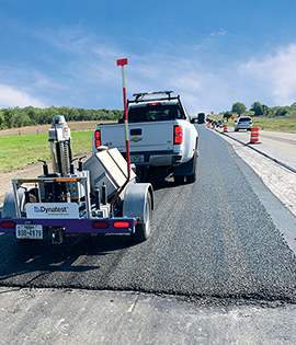 The use of Dynatest's falling weight deflectometer to test the pavement of a highway lane.