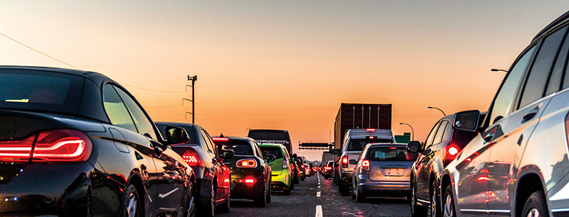 Congested freeway lanes at sunset.