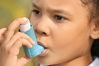 Young child using an inhaler for asthma.