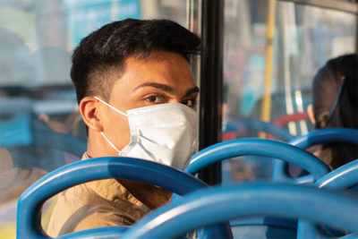 Young man wearing a mask while riding public transit.