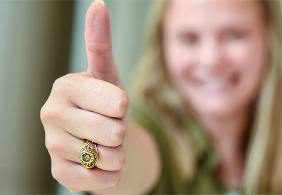 Texas A&M senior wearing Aggie ring giving the camera a Gig 'Em thumbs up.