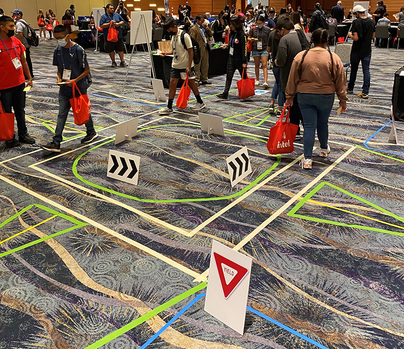 High School students participate in an interactive activity where they walk through a dummy intersection marked out on the floor.