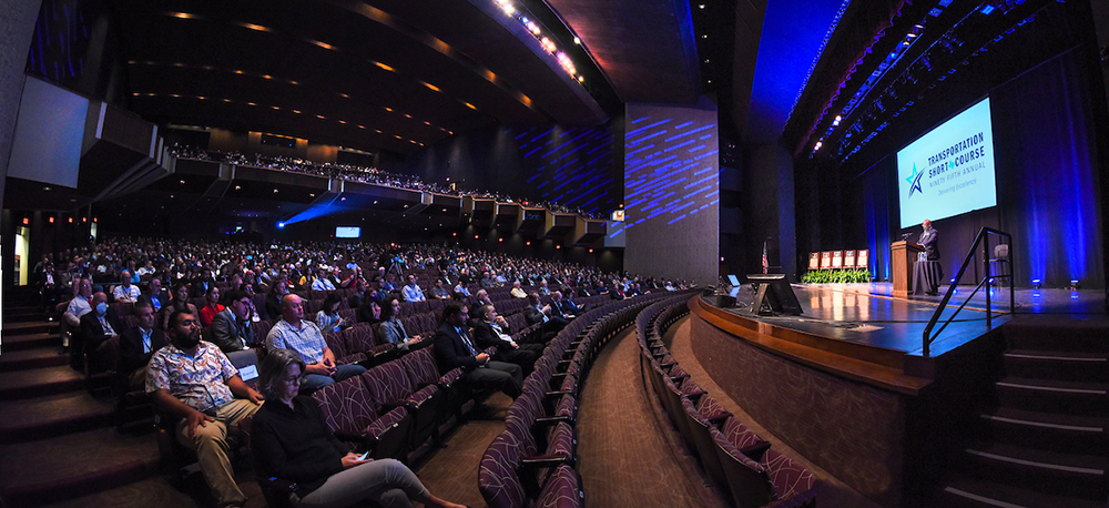 Photograph taken in the auditorium of the audience while Greg Winfree speaks on stage during the 2021 Transportation Short Course.
