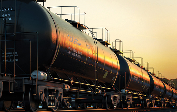Closeup photograph of a line of tanker cars linked up on a train track.