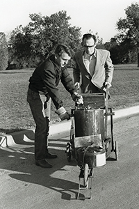 Historical photo of two men using striping equipment.