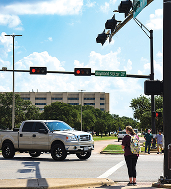 Intersection on the Texas A&M University campus with vehicle and pedestrian traffic.
