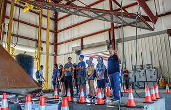Jett McFalls (far right) speaking to students in the rainfall simulator facility.