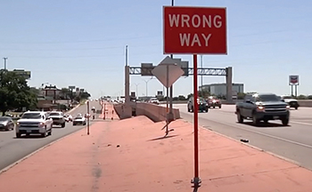 Example of a Wrong Way sign with red reflective tape in use along a stretch of freeway.