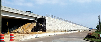 Photograph taken near an overpass showing how the retaining wall was widened to accommodate additional lanes.