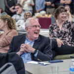 Stockton and others in the crowd laugh at a joke made during his retirement reception.