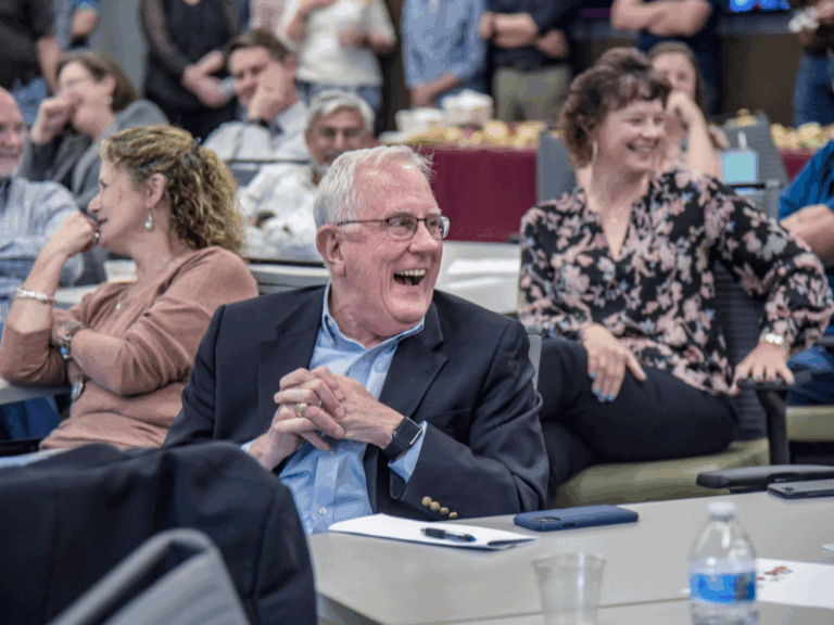 Stockton and others in the crowd laugh at a joke made during his retirement reception.