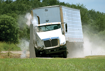 An 18-wheeler during a crash test with a concrete barrier and soundwall.