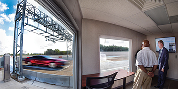 View from the Neology Transportation Research Center of a car passing under a toll gantry.