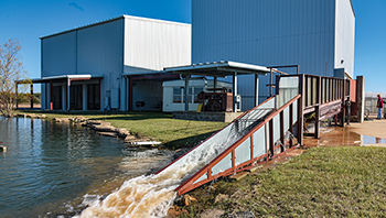 The Sediment and Erosion Control Laboratory's 30-foot outdoor variable slope channel flume with water running through it.