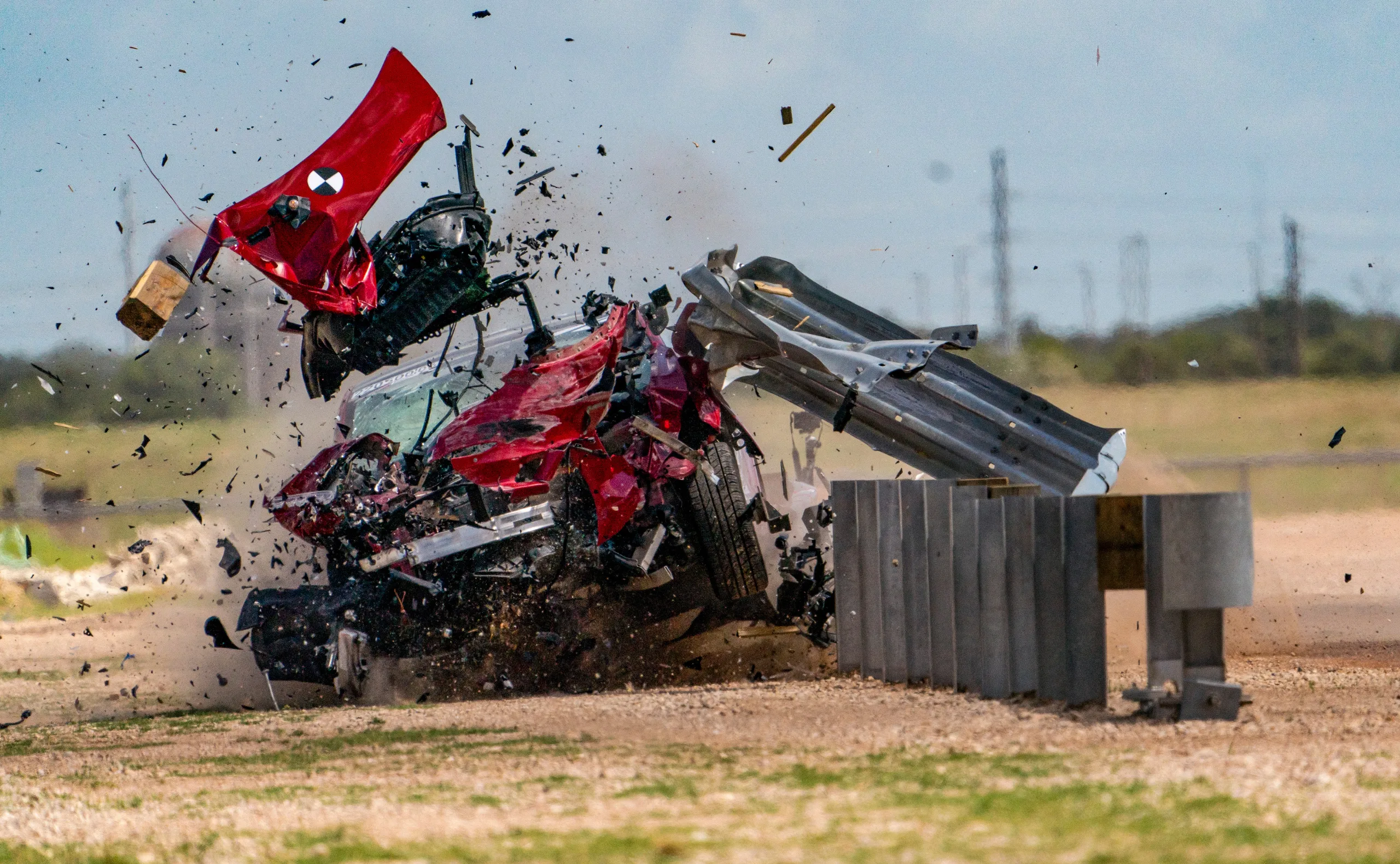 A red car crashes at high speed into a metal barrier