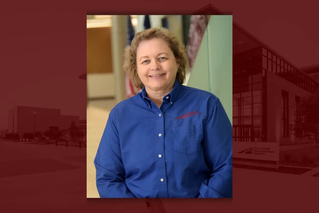 Darlene Goehl, Chief Engineer at TTI, stands indoors in a blue collared shirt, smiling at the camera.