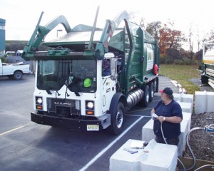 A refuse truck pulls up to a fueling station.