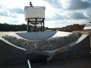 raised tank suspended on iron frame over gravel in metal concave container