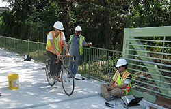 Workers test the traffic counter equipment by riding a bicycle through the sensor area.