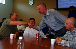 Stuart Denner (left) shakes hands with Walter Winkelmann during Stuart’s going-away celebration. Also pictured (left to right) are Brian Long and Andy Garner.