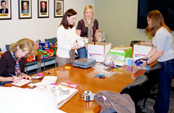 Sam Holland and Ashton Evans (right to left) pack boxes, while Michelle Hoelscher weighs the items and Terri Parker completes the U.S. Customs forms for the shipment.