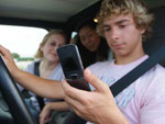 a teen texting and driving, with friends in the vehicle