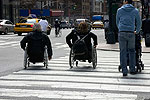two people in wheelchairs in a crosswalk