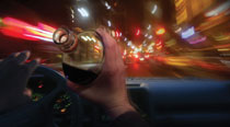 person drinking while driving automobile at night