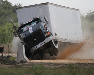 This is a photo of an 18-wheeler crashing into a concrete barrier as part of a crash test.