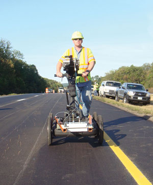 technician using the rolling density meter on a newly paved roadway