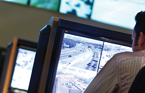 monitors in a traffic management center showing freeway camera feed